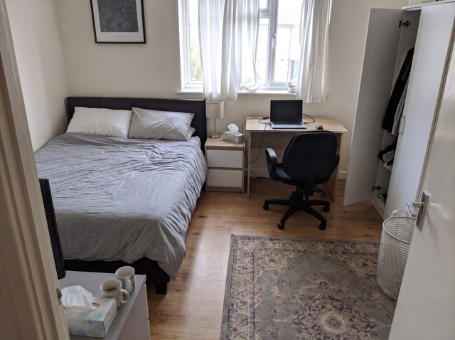 Dopo, con Riordina stanza: la stessa camera da letto con lo stesso letto, comodino, lampada, scrivania, portatile, sedia, armadio, tappeto e cesto della biancheria, ma senza vestiti, borsa, calzini né groviglio di cavi; le due tazze e la scatola di fazzoletti sono ancora sul cassettone in primo piano