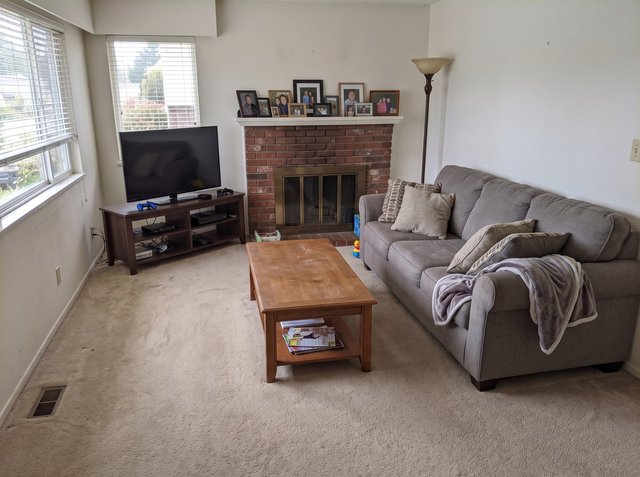 Attempt 1: the living room with the floor and coffee table cleared, but the family photos still on the mantel and a small toy and box still on the hearth