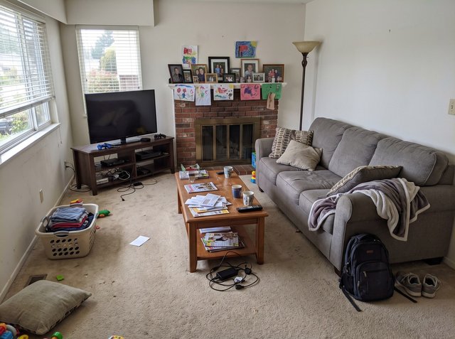 Before: a lived-in family living room with mail, mugs and a charger on the coffee table, a laundry basket, a backpack and sneakers on the carpet, and family photos and kids' drawings on the fireplace mantel